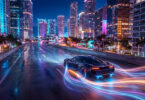 Une voiture de sport roulant sur une autoroute urbaine la nuit avec des traînées de lumière néon futuristes.